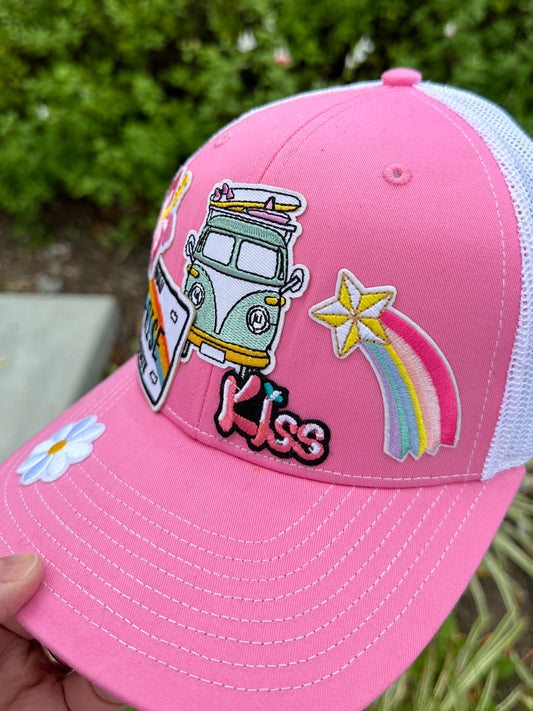 Pink cap with colorful patches including a van, rainbow, and 'Kiss' text.