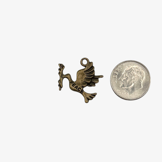 Bronze dove charm with 'PEACE' on a white background next to a quarter for scale.