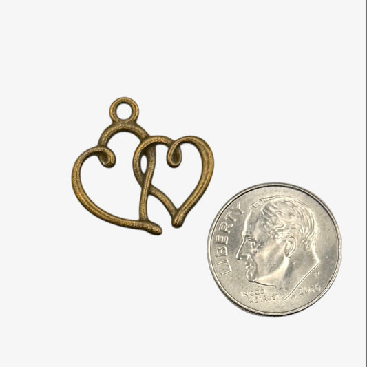 Bronze heart-shaped pendant next to a quarter for scale on a white background