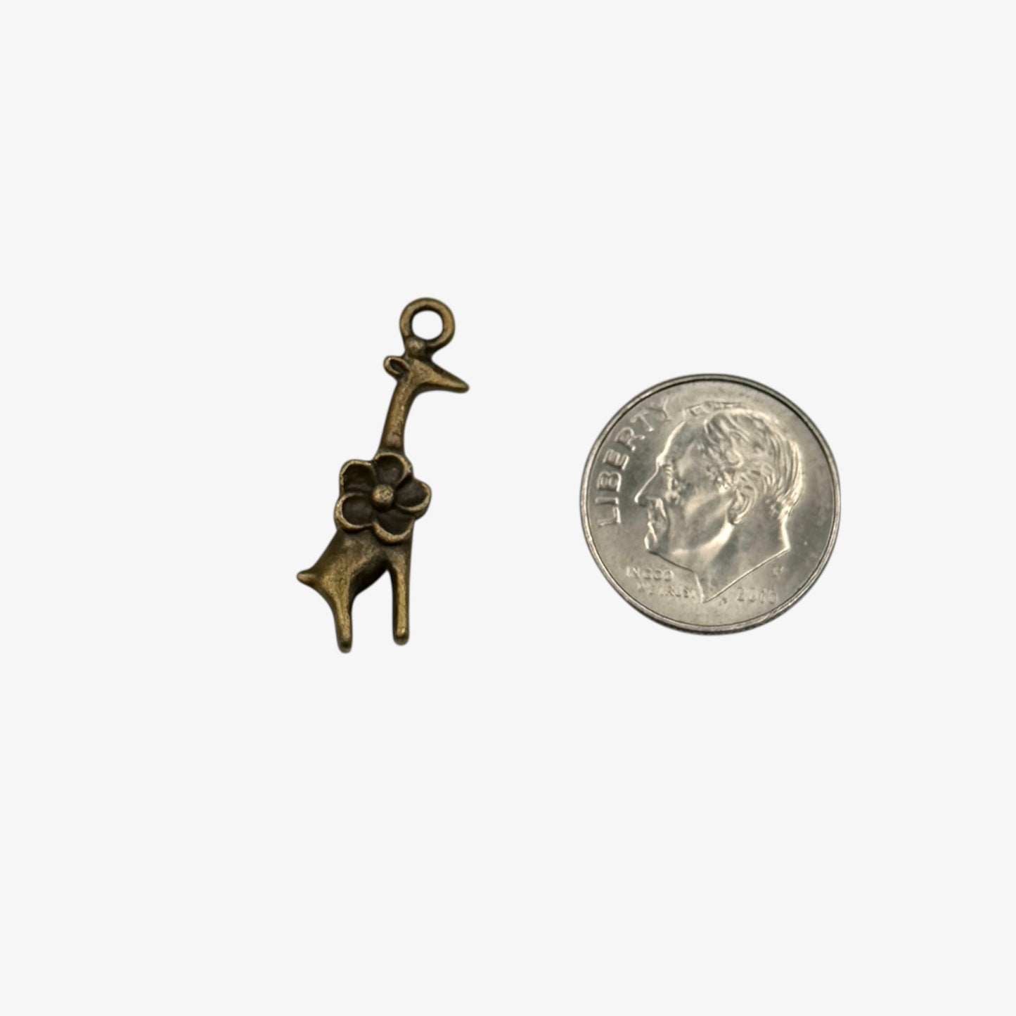 Bronze giraffe charm next to a quarter on a white background