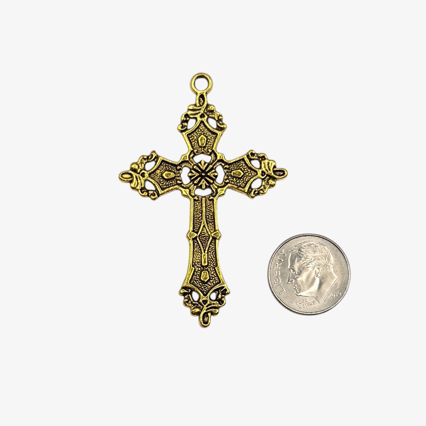 Gold cross pendant next to a coin on a white background