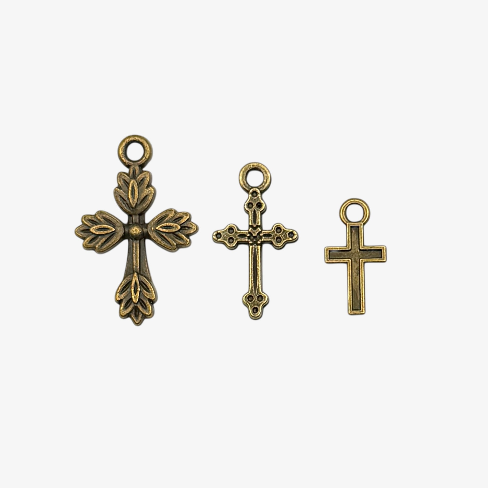 Three bronze cross pendants on a white background