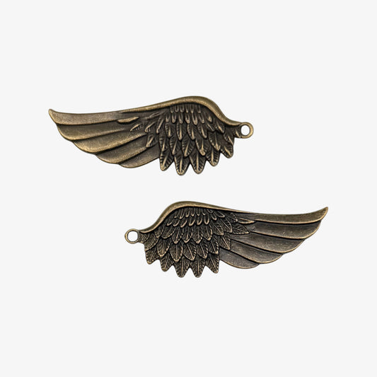 Two bronze angel wing charms on a white background