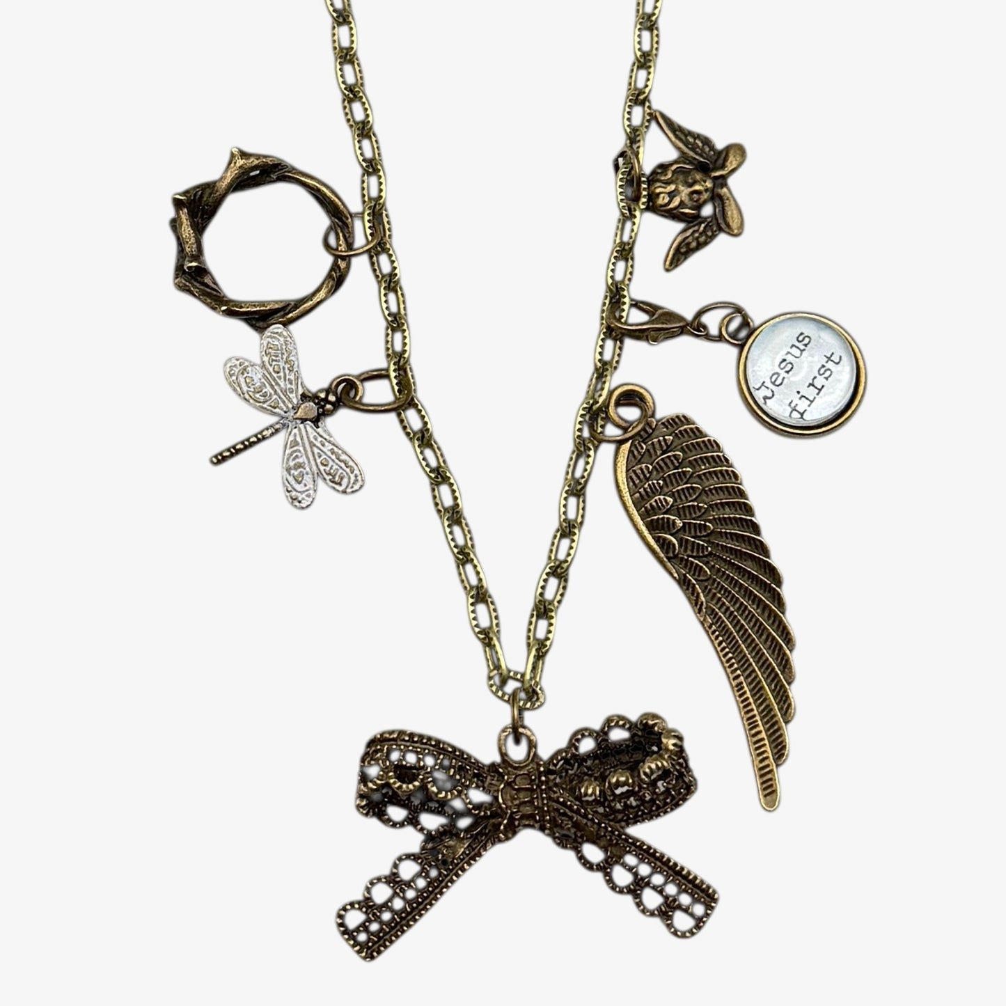 Bronze necklace with various charms including a bow, wing, and dragonfly on a white background.