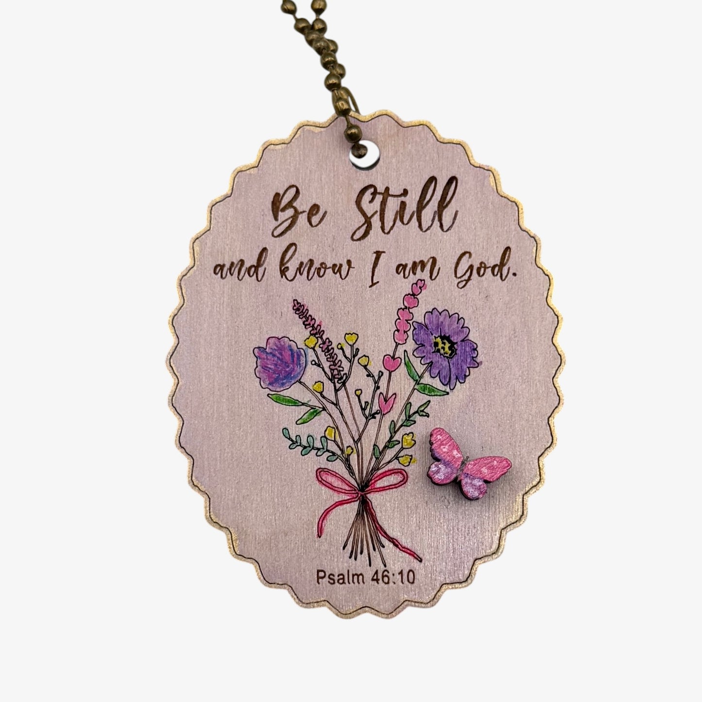 Wooden pendant with floral design and motivational quote on a white background