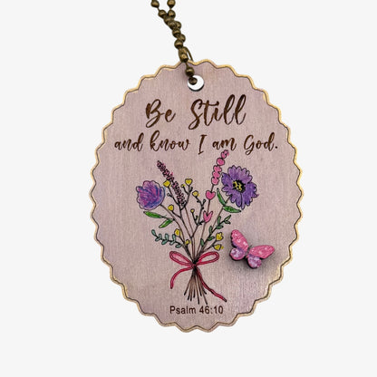 Wooden pendant with floral design and motivational quote on a white background