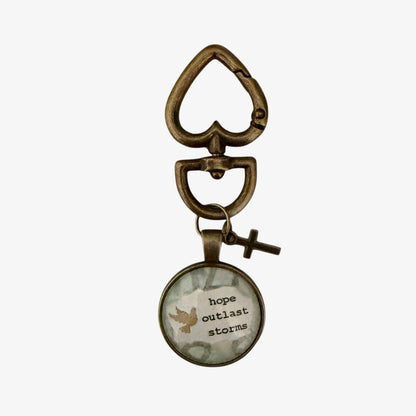 Bronze keychain with a circular pendant featuring text and a bird illustration on a white background