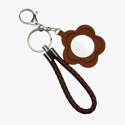 Brown leather keychain with flower-shaped tag on a white background