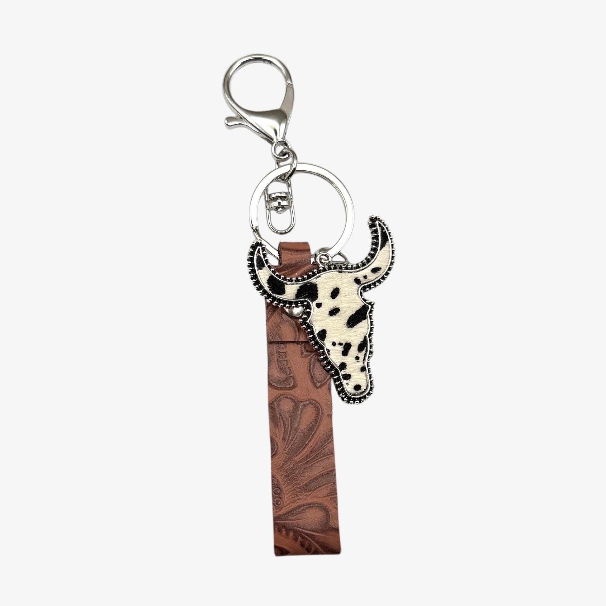 Keychain with cow head design and brown leather strip on a white background