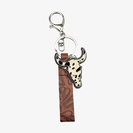 Keychain with cow head design and brown leather strip on a white background