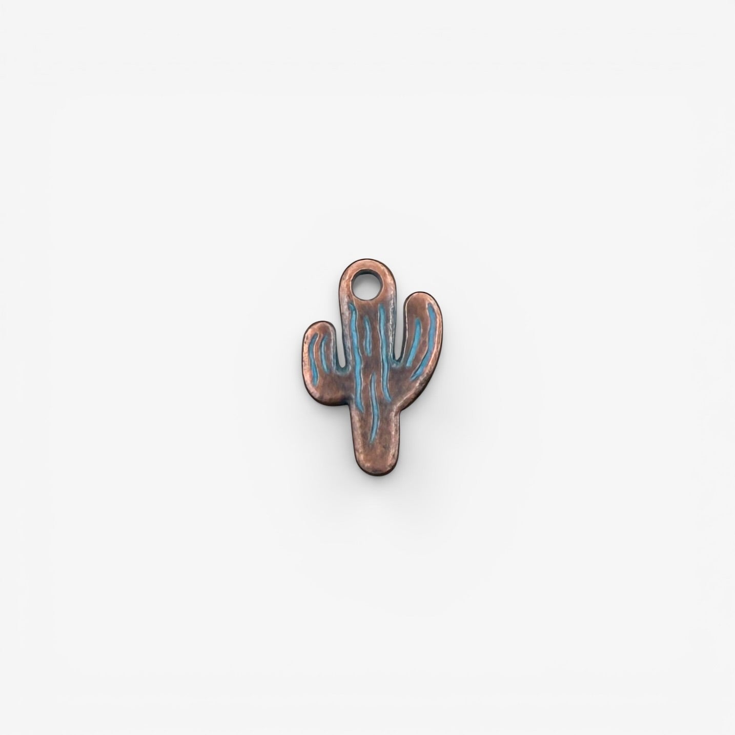 Cactus-shaped copper charm with blue engraving on a white background