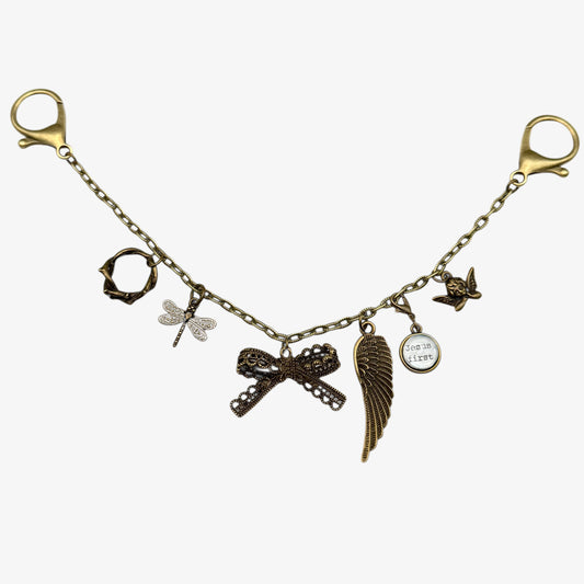 Bracelet with various charms including a bow, dragonfly, and angel wing on a white background