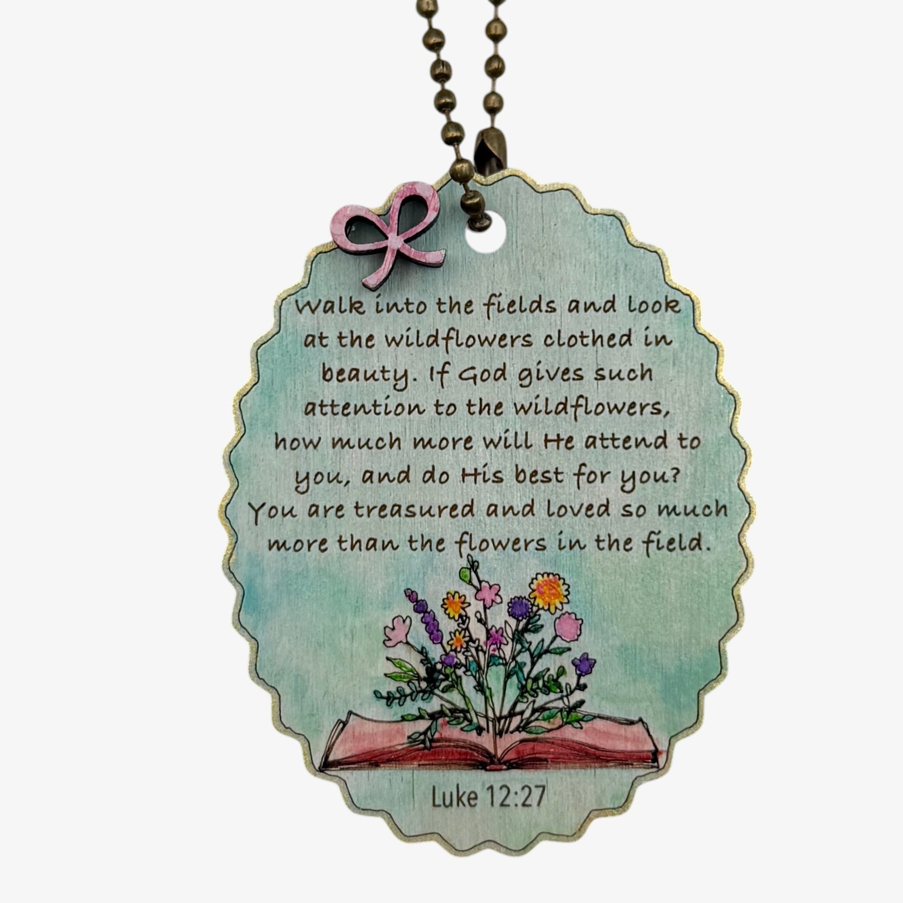 Necklace with pendant featuring a quote from Luke 12:27 and illustrations of flowers and an open book.