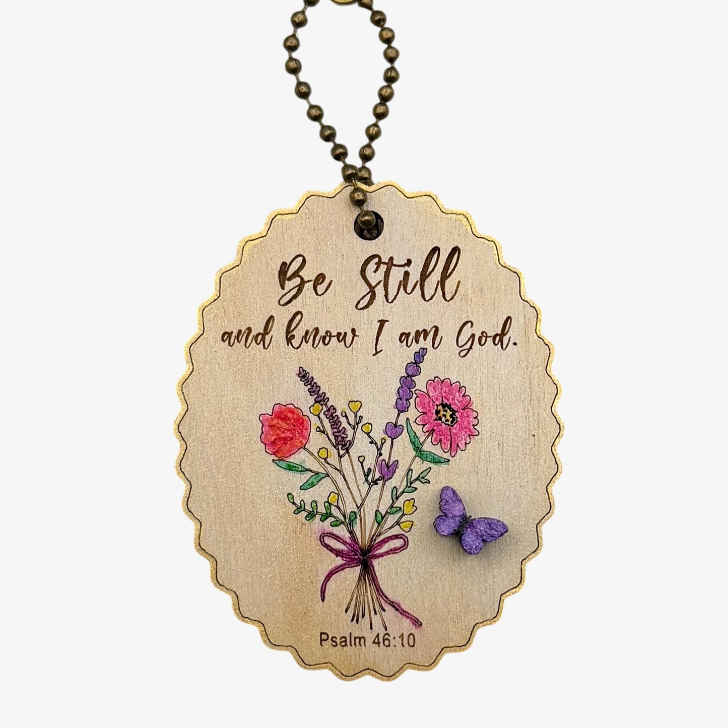 Wooden pendant with floral design and motivational quote on a white background