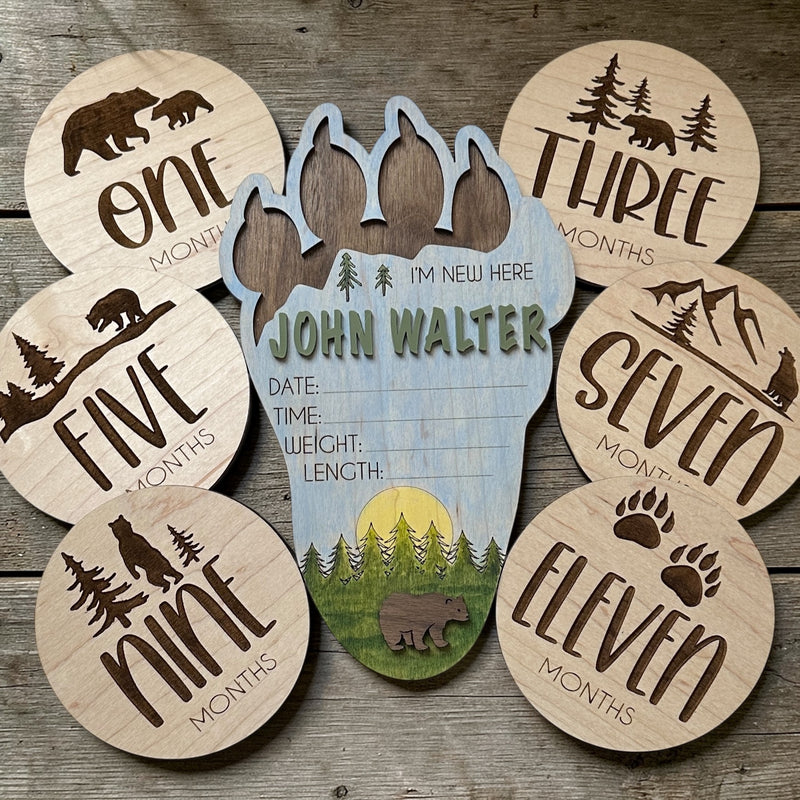 Wooden baby milestone cards with bear and tree designs on a wooden surface