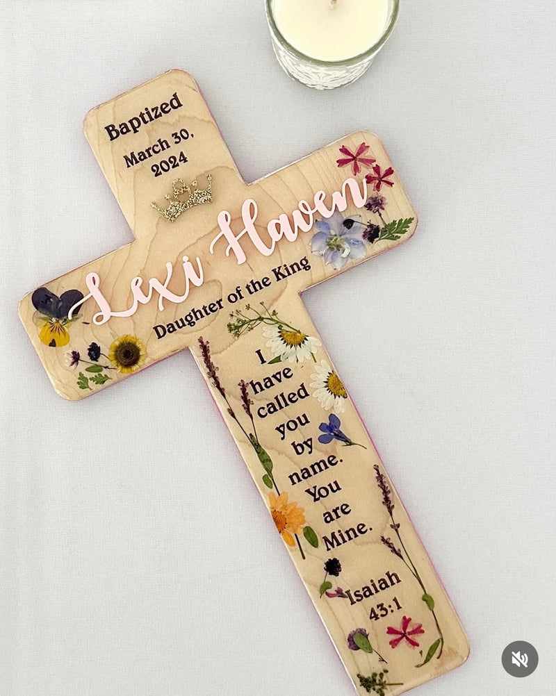 Decorative wooden cross with floral designs and text on a wood background