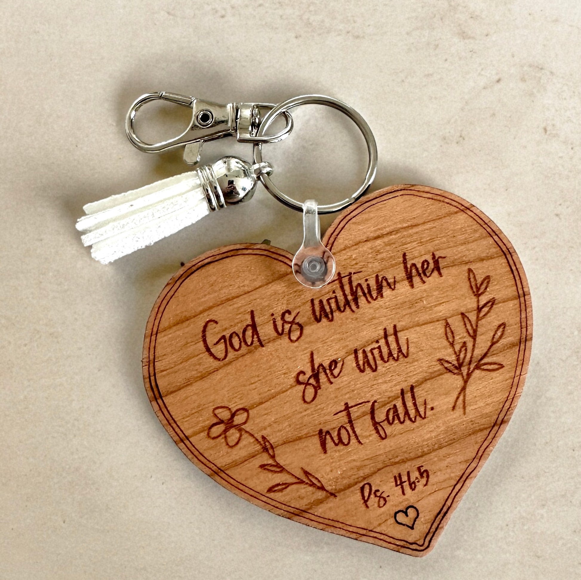 Wooden heart-shaped keychain with engraved text on a beige background