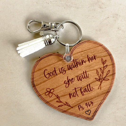 Wooden heart-shaped keychain with engraved text on a beige background