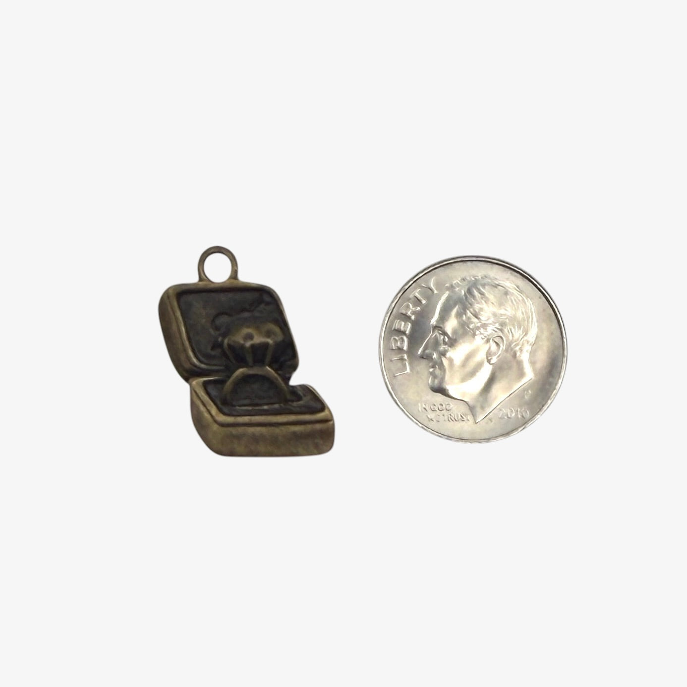 Bronze jewelry box charm next to a quarter for scale on a white background