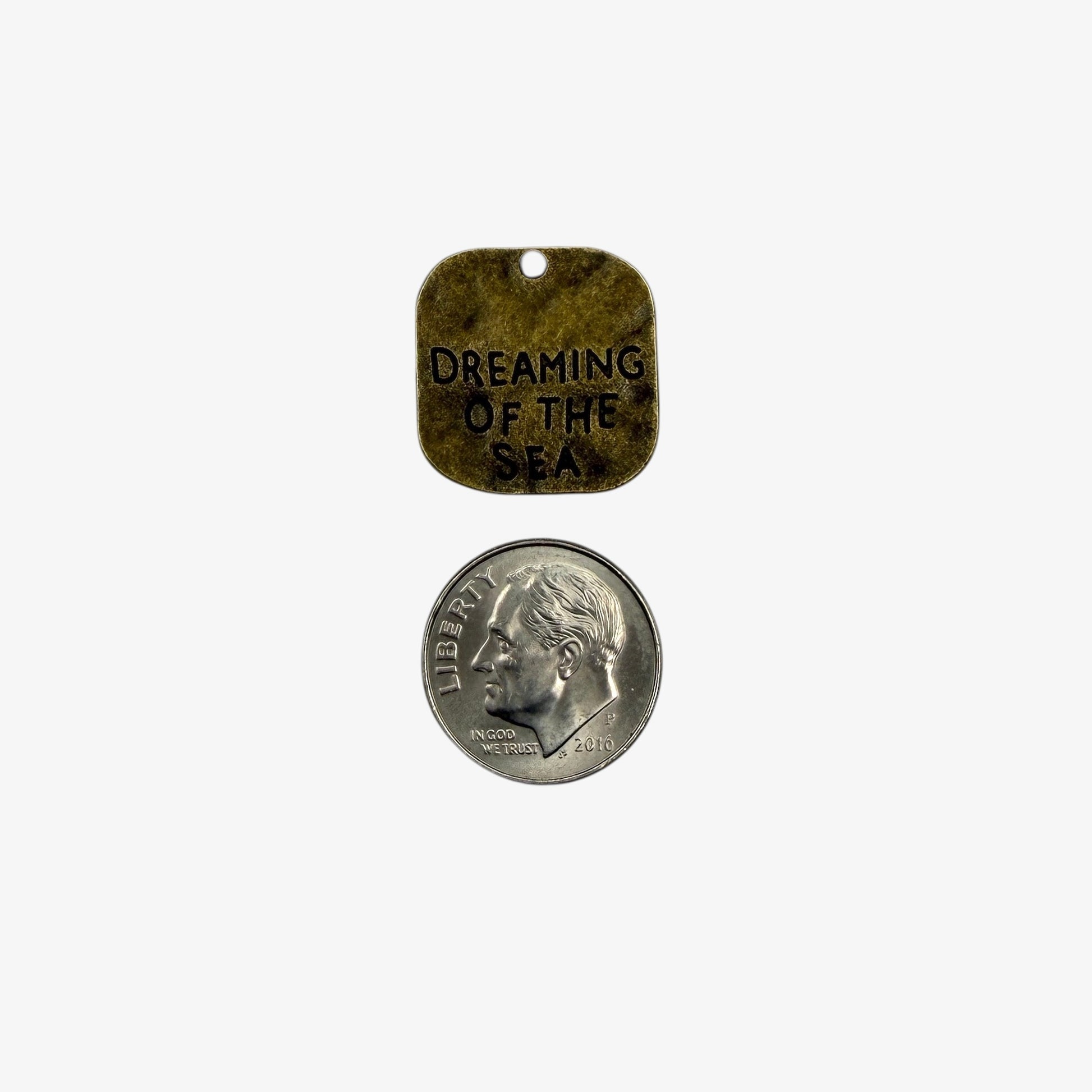 Small metal tag with 'Dreaming of the Sea' text 