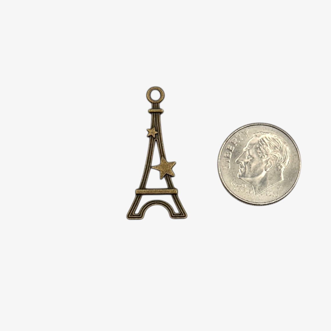 Bronze Eiffel Tower charm next to a U.S. quarter for size comparison on a white background