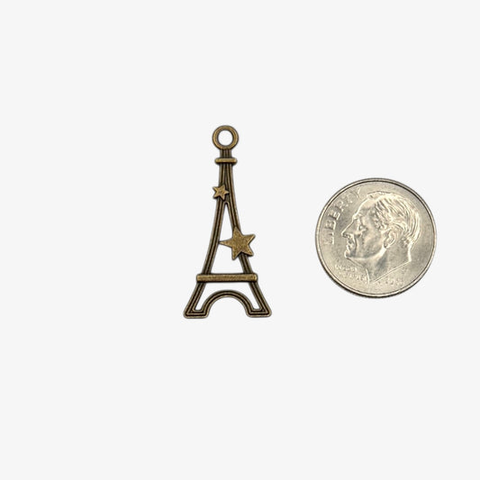 Bronze Eiffel Tower charm next to a U.S. quarter for size comparison on a white background