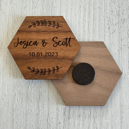 Hexagonal wooden coaster with engraved names and date on a light wooden surface
