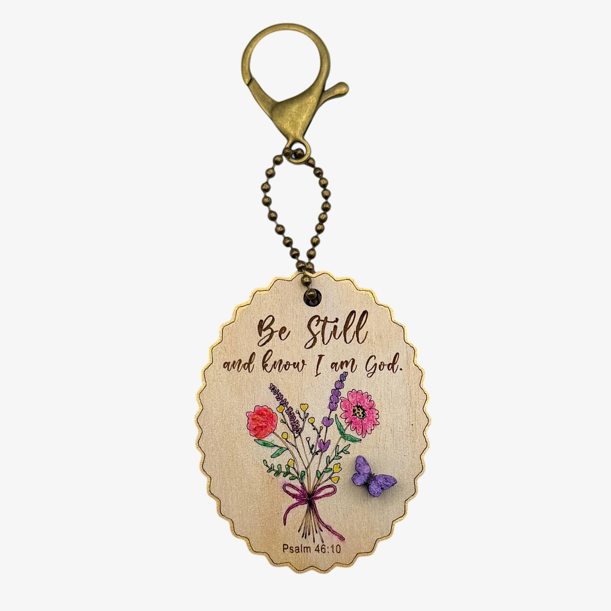 Decorative keychain with floral design and motivational quote on a beige background