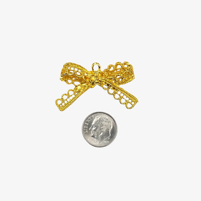 Gold bow-shaped pendant next to a silver coin on a white background