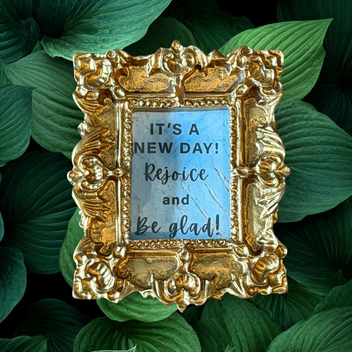Decorative gold frame with motivational quote on green leaves