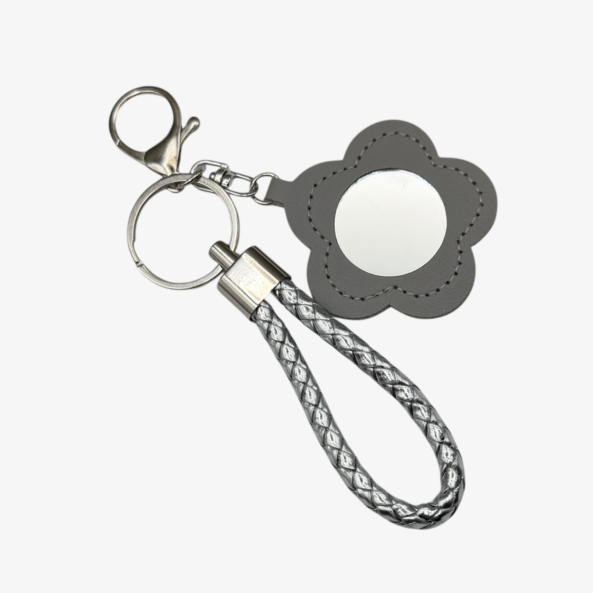 Keychain with flower-shaped mirror and braided strap on a white background