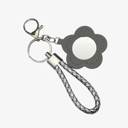 Keychain with flower-shaped mirror and braided strap on a white background