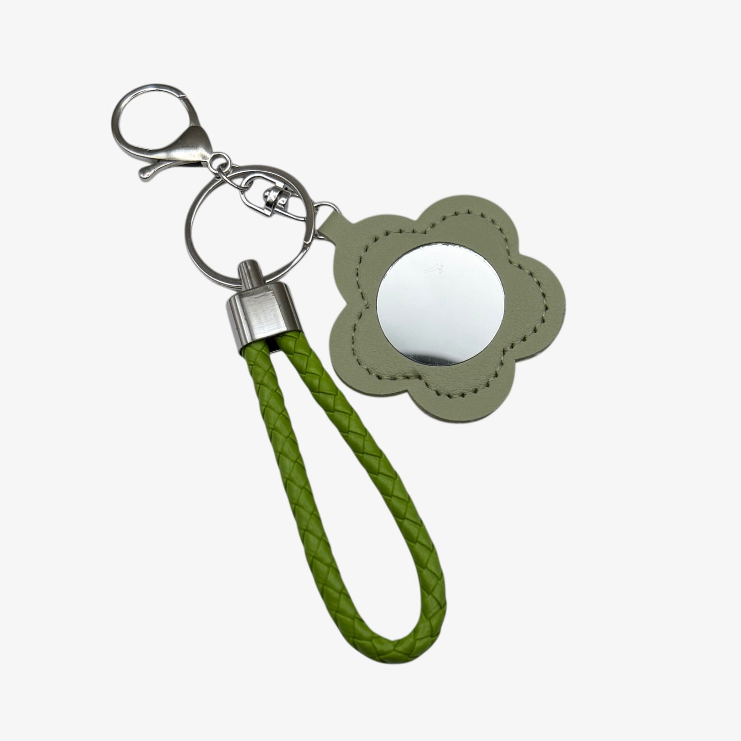 Keychain with green strap and flower-shaped mirror on a white background