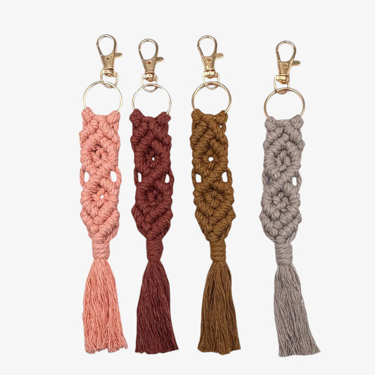 Four crocheted keychains in pink, red, brown, and gray on a white background