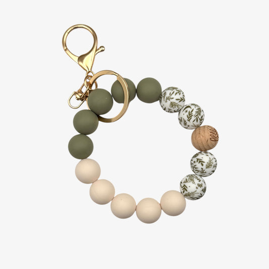 Beaded keychain with green, beige, and patterned beads on a white background