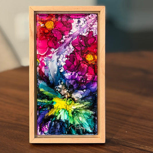 Colorful abstract painting in a wooden frame on a wooden surface