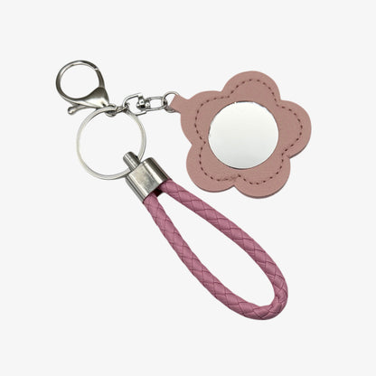 Pink flower-shaped keychain with a mirror and braided handle on a white background