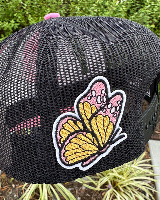 Black mesh cap with a butterfly patch on a blurred natural background