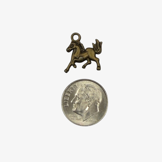 Small bronze unicorn charm next to a quarter on a white background