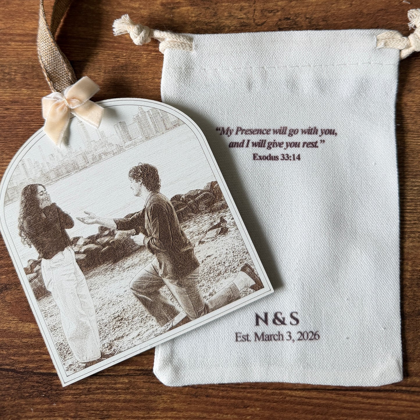 Personalized photo tag with a couple's picture and engraving, placed on a white drawstring bag.