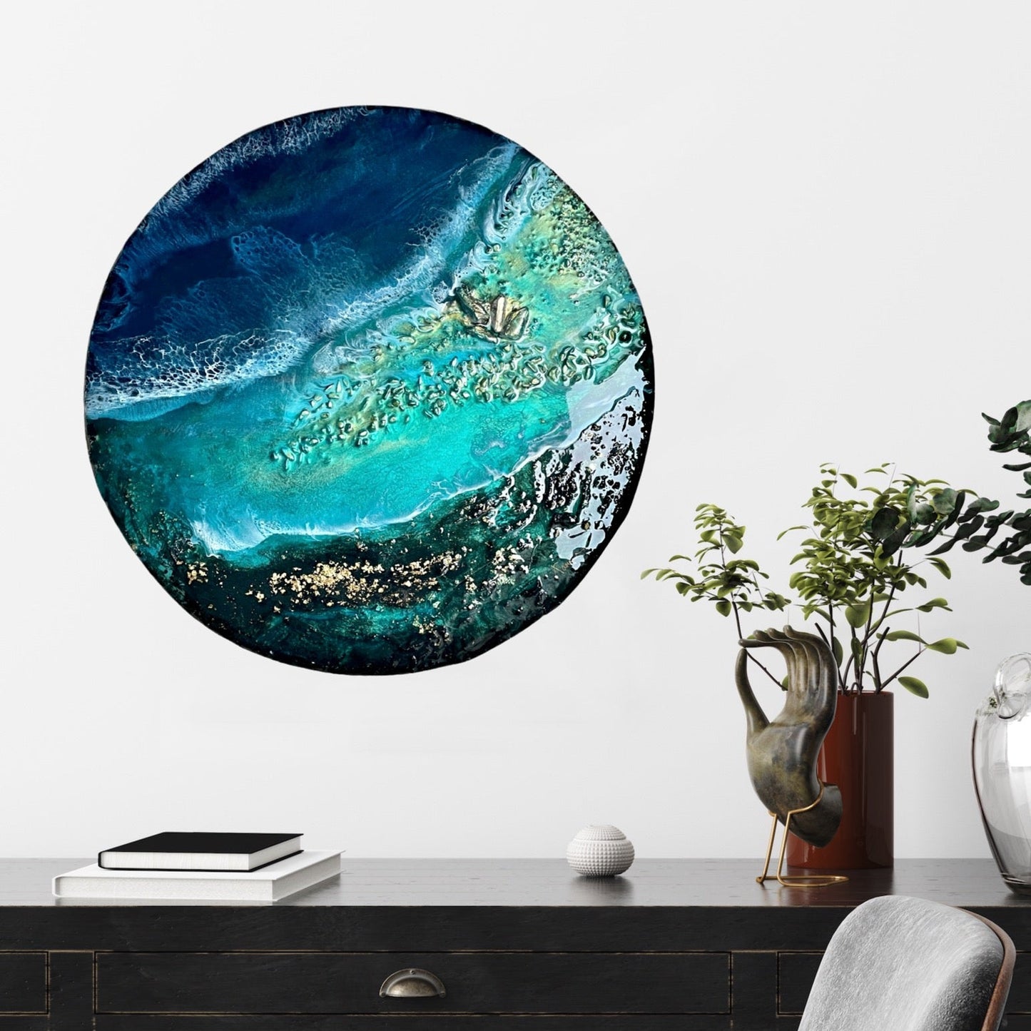 Round abstract artwork with blue and green colors on a wall above a desk.