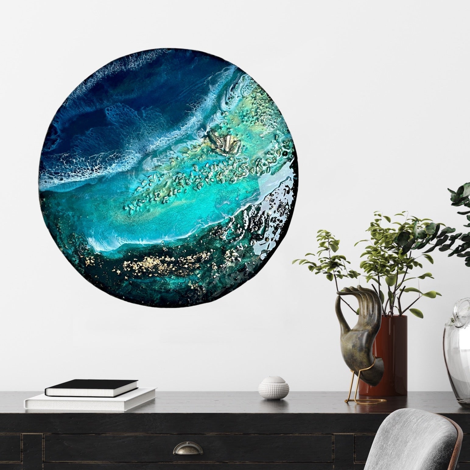 Round abstract artwork with blue and green colors on a wall above a desk.