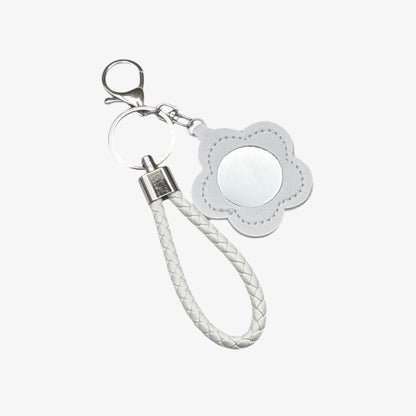 Keychain with white braided rope and flower-shaped tag on a white background