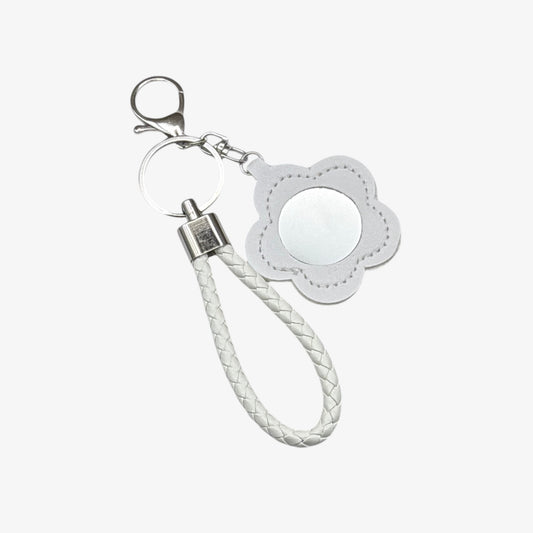 Keychain with white braided rope and flower-shaped tag on a white background