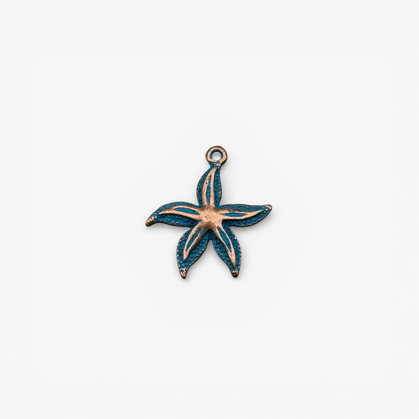 Starfish-shaped pendant with copper and blue enamel on a white background