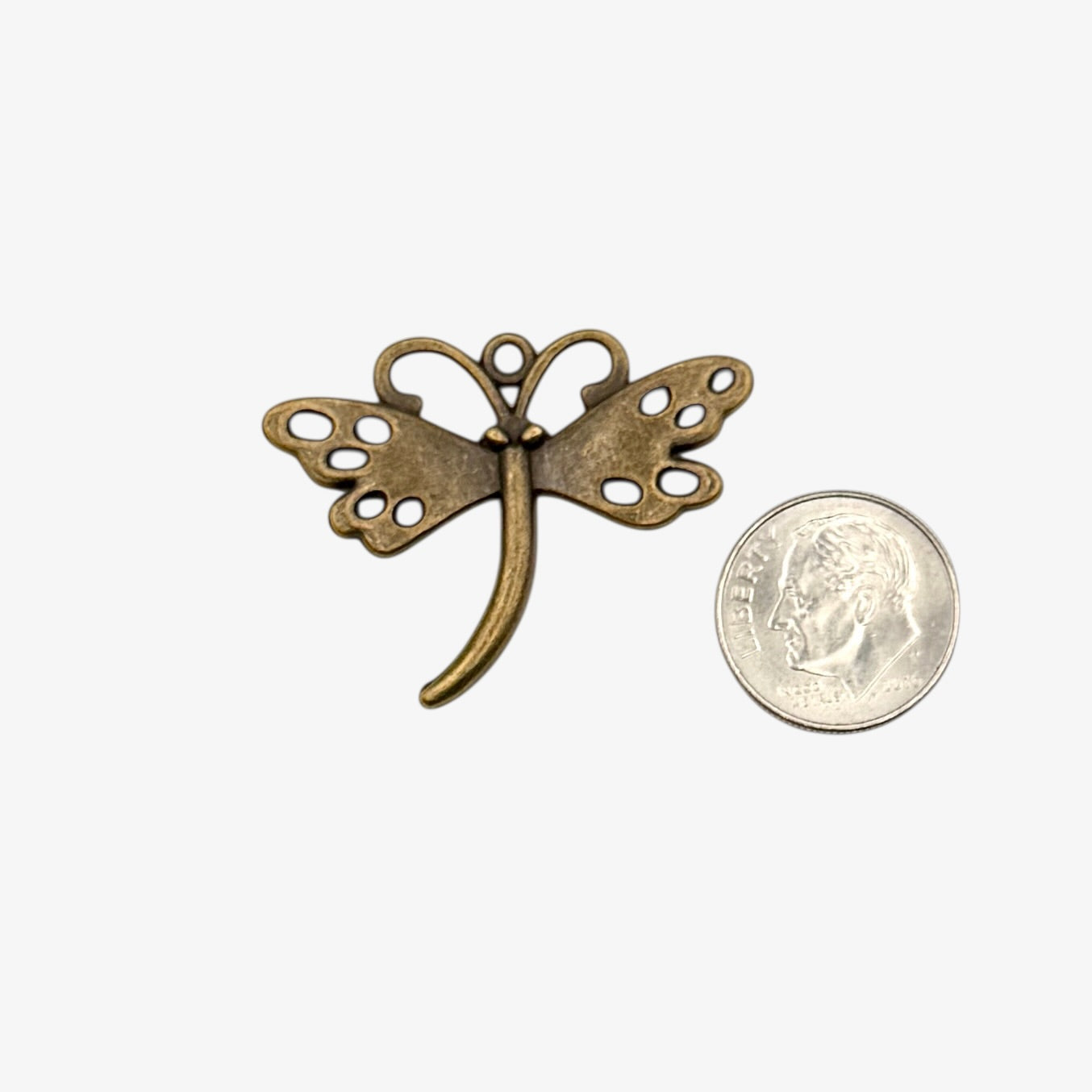 Bronze butterfly-shaped pendant next to a U.S. quarter coin on a white background