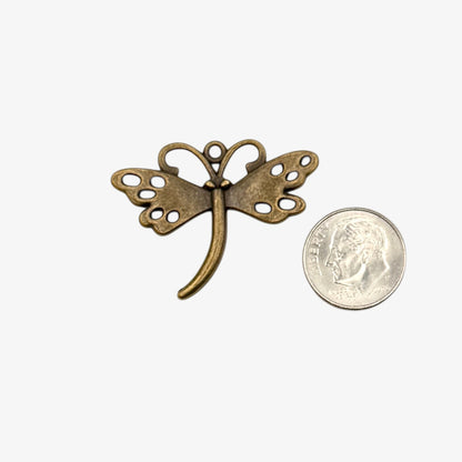 Bronze butterfly-shaped pendant next to a U.S. quarter coin on a white background