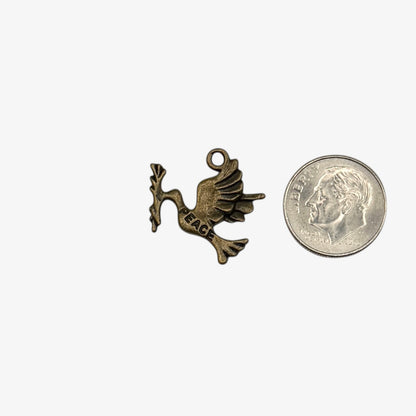 Bronze dove charm with 'PEACE' on a white background next to a quarter for scale.