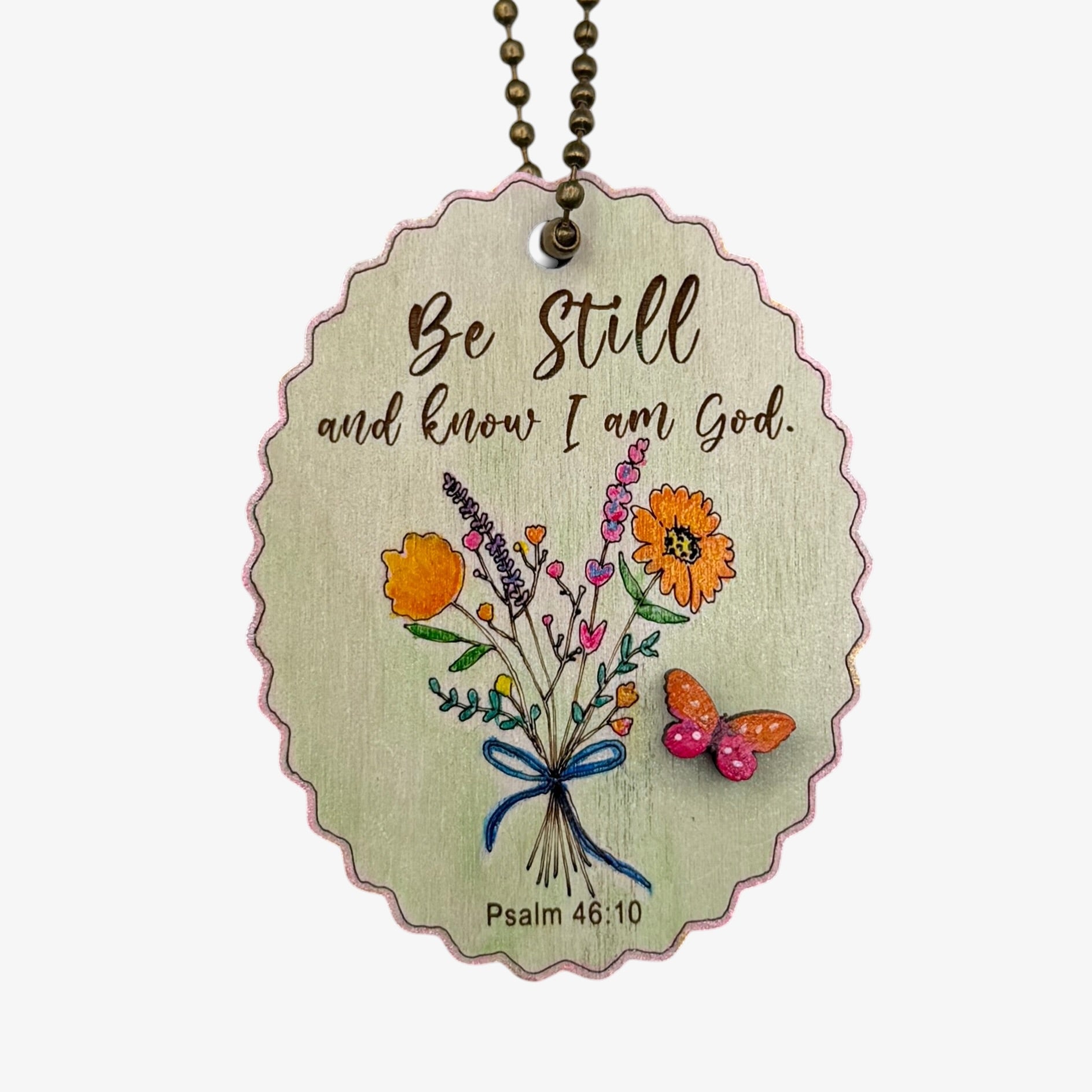 Decorative pendant with floral design and text 'Be Still and know I am God' on a white background