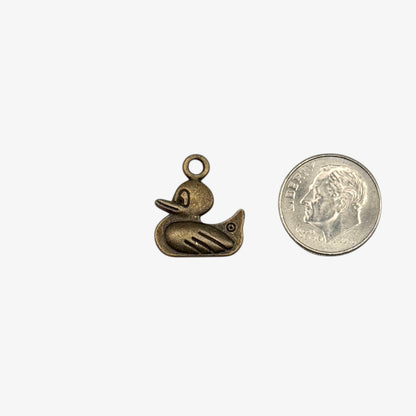 Bronze duck-shaped pendant next to a U.S. quarter for size comparison on a white background